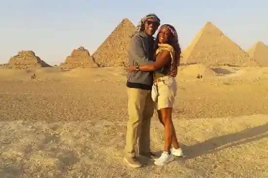 A romantic couple hugging and posing for a photo in front of the Great Pyramids.