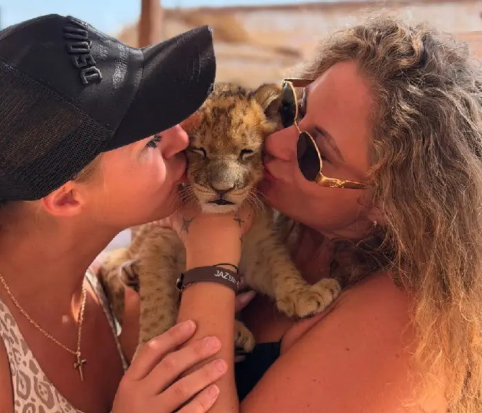 Two women kissing a cute baby lion cub on the cheeks in Hurghada